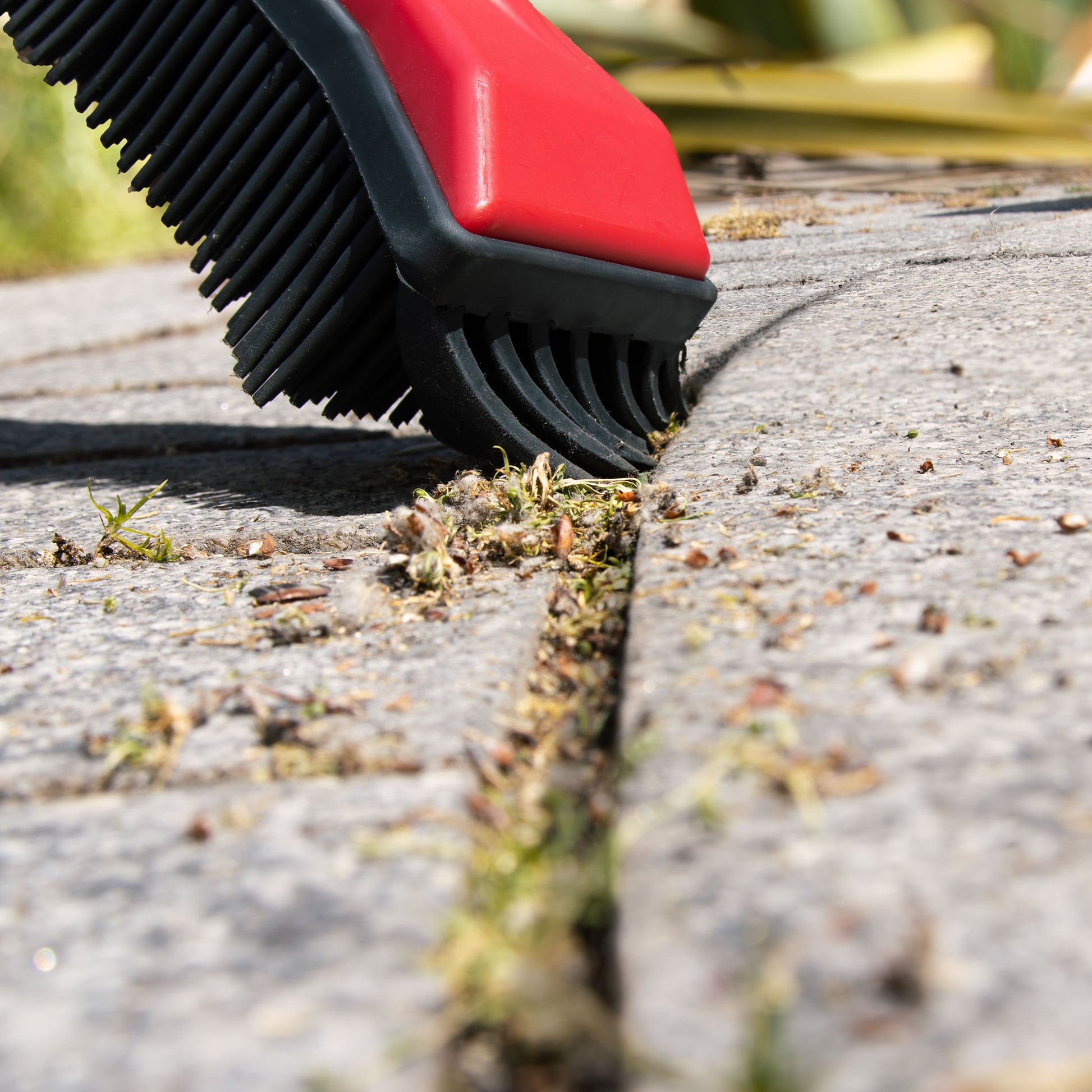 Garden broom clearing debris from block-paving cracks